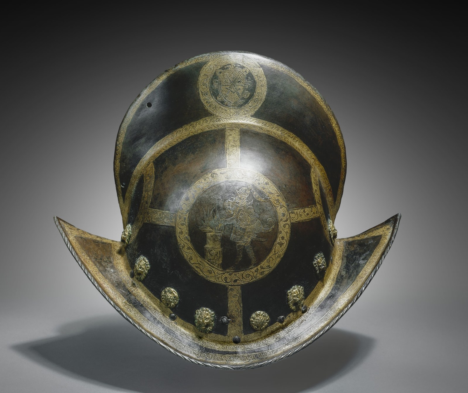 A high central ridge and a sharply curved brim define the helmet. Gilded bands and circular decorative fields stand out against darkened steel.